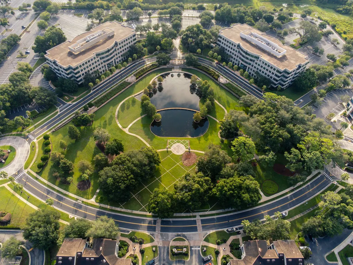 An aerial view of office buildings set among landscaped lawns, trees and curving paths.